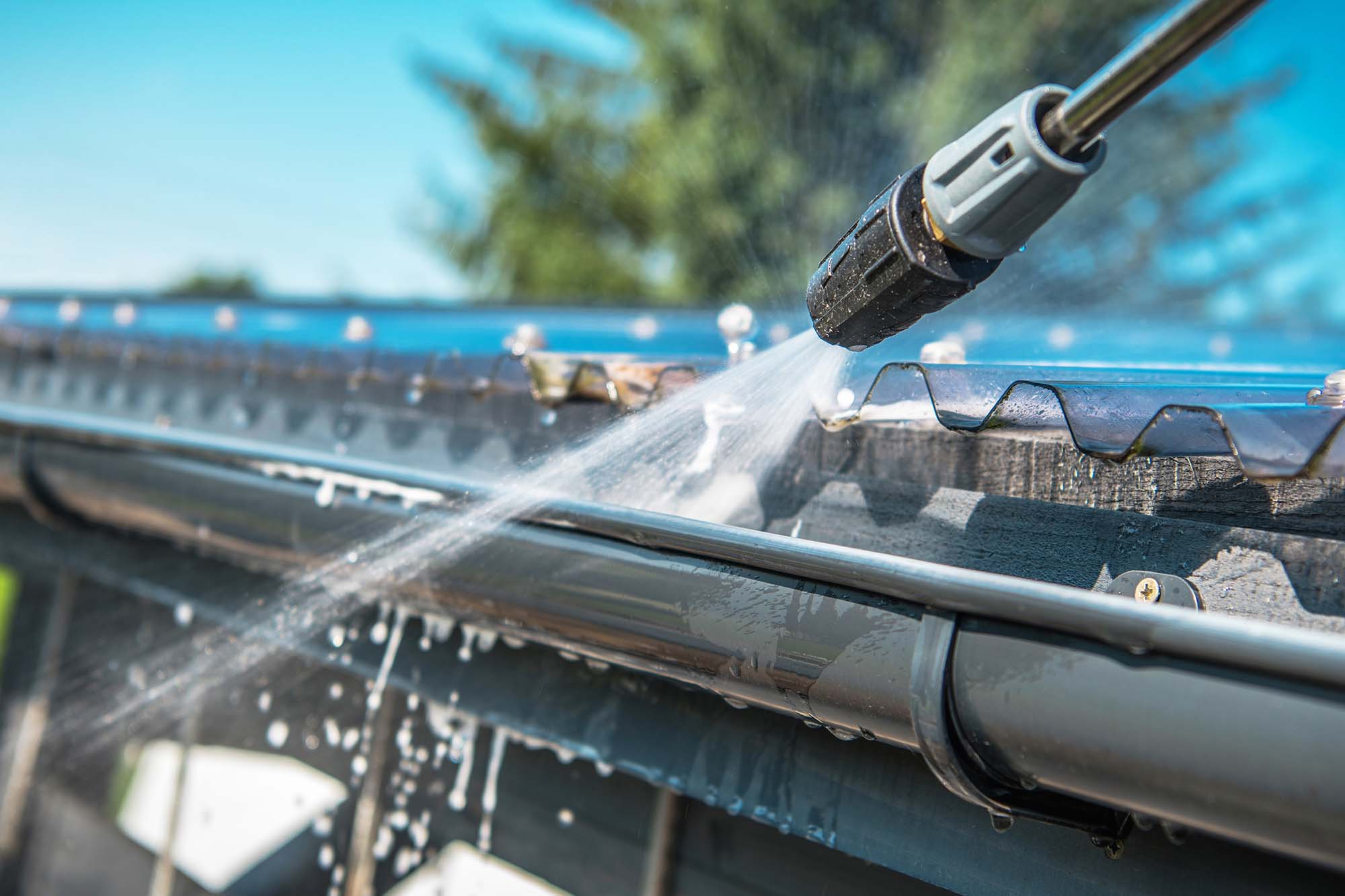 GuttersHero Rain Gutters Pressure Cleaning. Spring Rain Gutters Cleaning Using Pressure Washer. Closeup Photo.